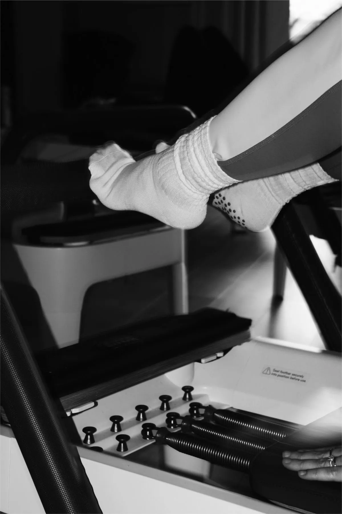Pieds en chaussettes posés sur la barre d'un reformer, ressorts au premier plan